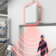 Fixed RFID antenna projecting red concentric signal waves over a warehouse doorway for automated tracking.